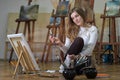 Woman artist sits on the floor in art studio and paints Royalty Free Stock Photo