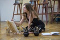 Woman artist sits on the floor in an art studio and paints Royalty Free Stock Photo