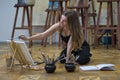 Woman artist sits on the floor in art studio and paints Royalty Free Stock Photo