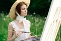 woman artist view with paint palette draws a picture in nature