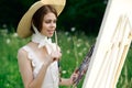 woman artist view with paint palette draws a picture in nature