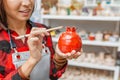 Woman artist in working apron paints with brush a decorative ceramic pottery in workshop Royalty Free Stock Photo