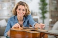 woman as trainee cleaning guitar in guitar maker workshop