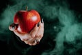 Woman as witch offers red apple as symbol of temptation, poison. Royalty Free Stock Photo