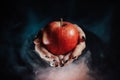 Woman as witch offers red apple - symbol of toxic proposal, lure. Royalty Free Stock Photo