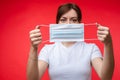 Woman with aseptic mask in hands. Isolate on red.