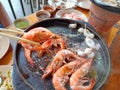 woman asia hand holding chopsticks grilled shrimp on a hot pan, on a wooden table Royalty Free Stock Photo