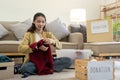 Woman asian holding donation box full with clothes and select clothes. Concept of donation and clothes recycling