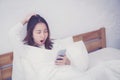 woman asian model holding a mobile phone with wake up in bedroom. Royalty Free Stock Photo