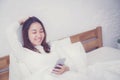 Woman asian model holding a mobile phone with wake up in bedroom. Royalty Free Stock Photo