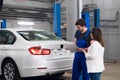 A woman asks a repairer about a car repair Royalty Free Stock Photo