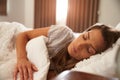 Woman Asleep In Bed As Sunlight Comes Through Curtains Royalty Free Stock Photo