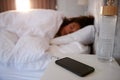 Woman Asleep In Bed With Mobile Phone On Bedside Table Royalty Free Stock Photo