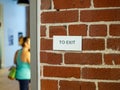 Woman in athletic clothes with in direction of exit sign on brick wall Royalty Free Stock Photo