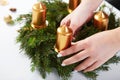 Woman attaches candle on a Christmas wreath