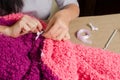 a woman attaches a white bow to a knitted by hand lilac-pink plaid