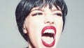 Woman with attractive red lips shouting. Lady in black wig with make up on grey background. Girl on scandalous shouting