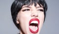 Woman with attractive red lips shouting. Lady in black wig with make up on grey background. Girl on scandalous shouting