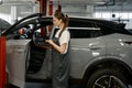 Woman auto mechanic checking customer car using laptop for diagnostics