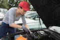 Woman auto mechanic fixing engine car outdoors