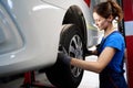 Woman auto mechanic removes a car wheel