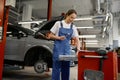Woman auto mechanic taking instrument for work from toolkit box