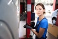 Woman auto mechanic works with a car on car lift