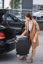 Woman in autumn clothes holding suitcase