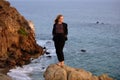 Woman in autumn fashion dress on the ocean coast, on rocky beach.