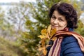 Woman in the autumn forest with a happy look holds an oak branch in her hand. A walk in the woods