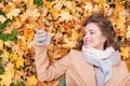 Woman on autumn leaves taking selfie by smartphone Royalty Free Stock Photo