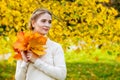 Woman in an autumn park. An emotional portrait of a cute and positive beautiful blonde girl with a bouquet of maple leaves on a Royalty Free Stock Photo