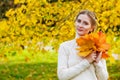 Woman in an autumn park. An emotional portrait of a cute and positive beautiful blonde girl with a bouquet of maple leaves on a Royalty Free Stock Photo