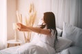 Woman awakening stretching in bed in early morning