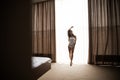 Woman is awoke and standing before window. Royalty Free Stock Photo