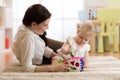Mother and baby girl playing with developmental toys in nursery room