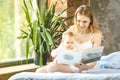 Woman and baby girl reading. Mother and her little baby girl on bed Royalty Free Stock Photo