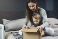 Woman and baby unpacking cardboard box with surprise. International shopping with shipment worldwide Royalty Free Stock Photo