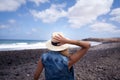 Woman back with hat. looking over the sea. standing on a stones beach. Royalty Free Stock Photo