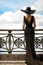 Woman Back Side View in Hat and Evening Dress Outdoor. Fashion Model Rear View looking away. Luxury Lady in long Gown at Promenade