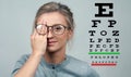 Woman on the background of eye test chart, eye care concept Royalty Free Stock Photo