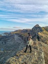 A woman on the background of the rocky coast of the Barents Sea. Beautiful view of the cliffs and the coast of the