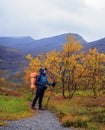 A woman with a backpack in the autumn season walks along a path in the mountains on a rainy day. Royalty Free Stock Photo