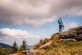 Woman with backpack and camera climbing at mountain peak