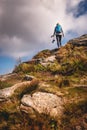 Woman with backpack and camera climbing at mountain peak