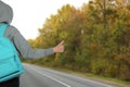 Woman with backpack catching car on road, closeup. Hitchhiking trip Royalty Free Stock Photo