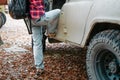 A woman with a backpack climbs into a suv. Trees in the background. Close up. Concept of car travel and tourism