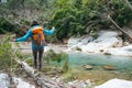 A woman with a backpack crosses a river on a log Royalty Free Stock Photo