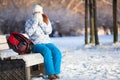 Woman with backpack heats hands in mittens at winter, copyspace