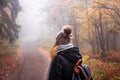 Woman with backpack and knit hat hiking in foggy forest Royalty Free Stock Photo